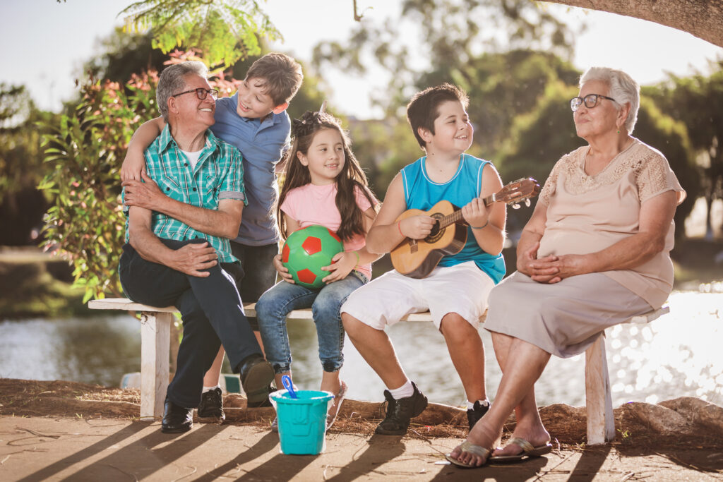 Smiling Hispanic family sitting on a bench next to a lake.