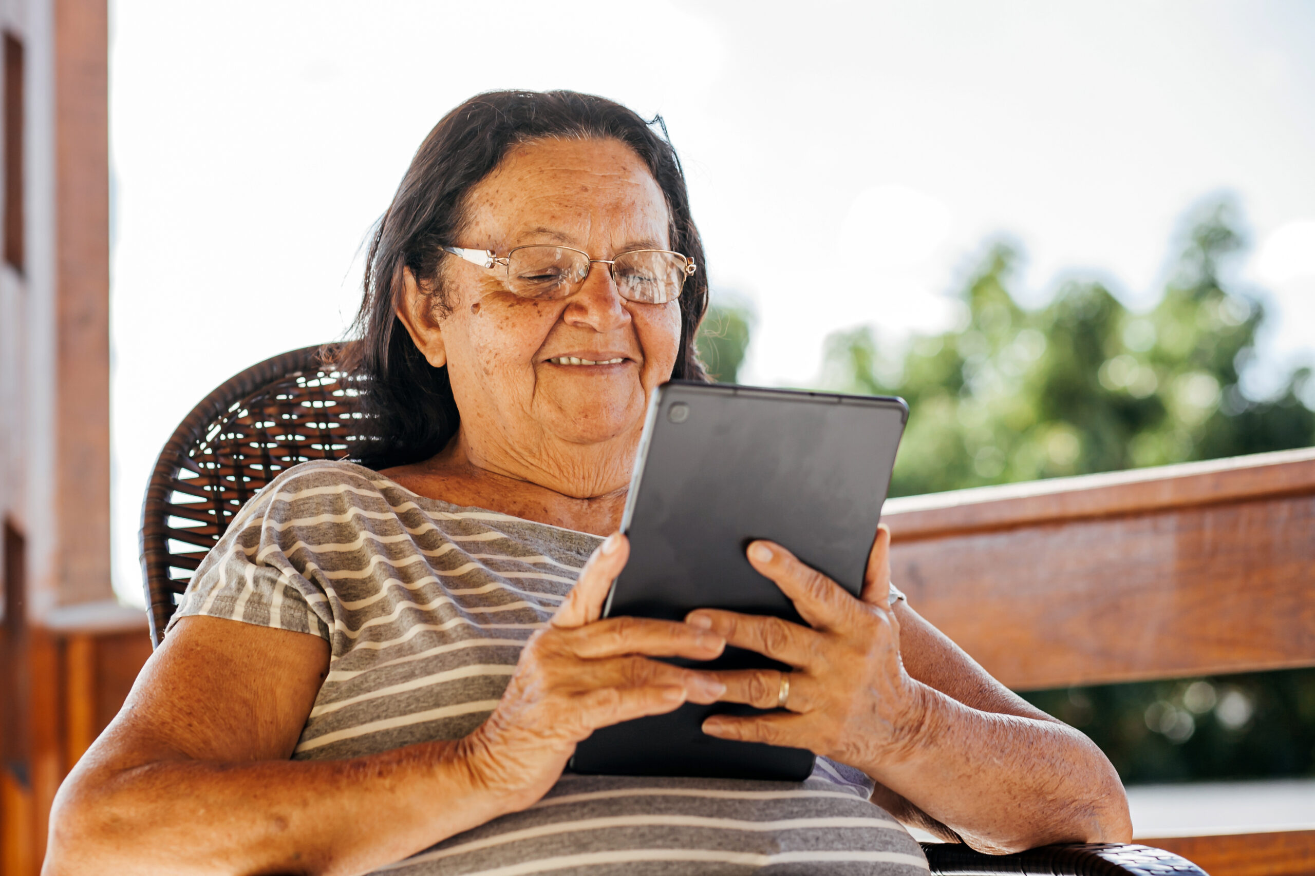 Older Latin women sitting and smiling at her tablet